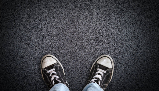 一个穿着牛仔裤和帆布鞋的少年站在有复制空间的柏油路上站在十字路口思图片