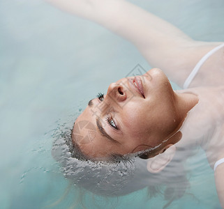 在度假时在游泳池里漂浮在水中一位年轻女子的头图片