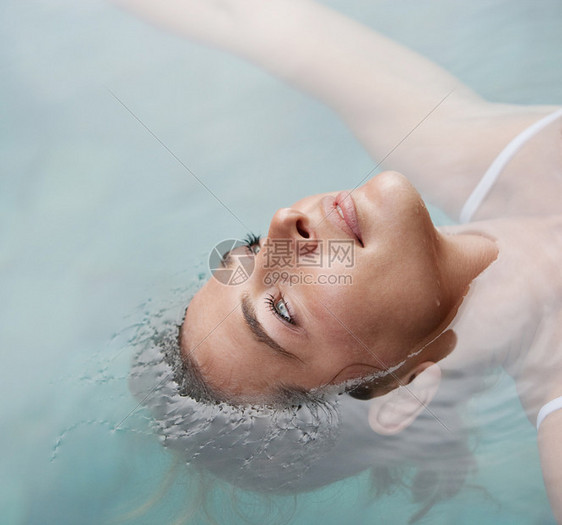 在度假时在游泳池里漂浮在水中一位年轻女子的头图片