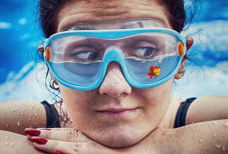 戴游泳眼镜的年轻女子半装水和一条鱼图片