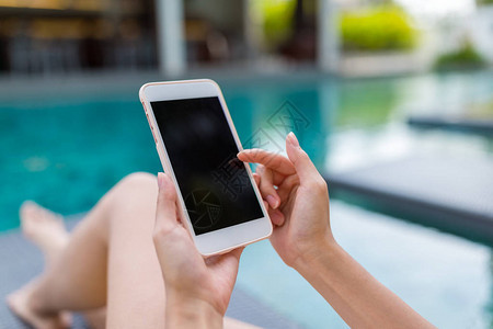 妇女使用她的手机和在游泳图片
