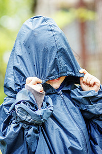 有趣的小男孩在雨中行走穿着雨衣图片