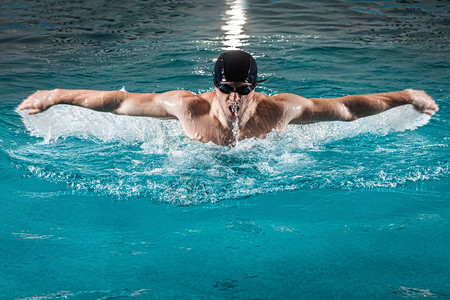 肌肉发达的年轻人在游泳池里游蝴蝶背景图片