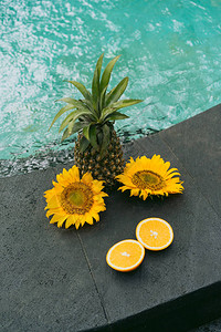 在游泳池近距离观看菠萝切橙子和美丽的黄色花图片