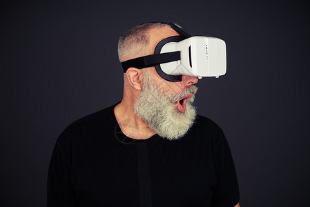 胡子老人惊讶使用虚拟现实眼镜黑色背图片