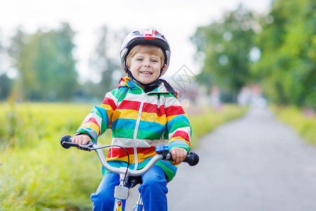 在暑假第一辆自行车上驾驶的红色安全头盔活跃男孩图片