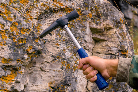 地质学家亲手用地质锤子击打石灰岩质图片