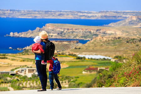 背包,带着两个孩子的母亲在风景路上旅背景