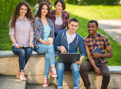 一群年轻迷人的微笑学生穿着休闲装坐在大学校园图片