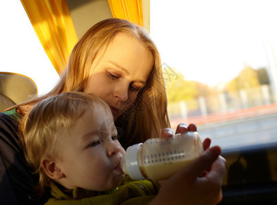 年轻母亲正在用牛奶喂养她两岁的儿子图片