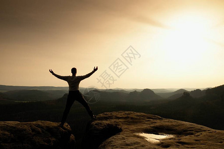 快乐的男人在露天悬崖上举起的手势胜利图片
