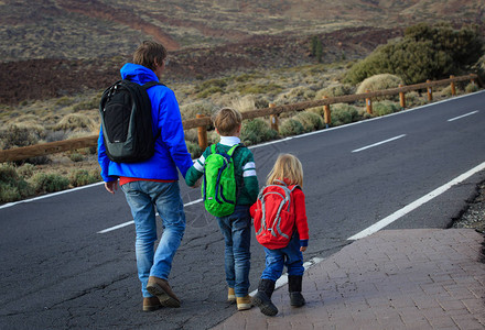 父亲和两个孩子在山上路行走图片