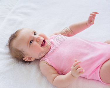 4个月大笑着快乐的女婴在床上休息背景图片