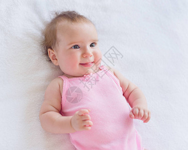 四个月大的快乐兴奋的女婴在床上背景图片