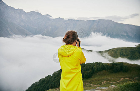 一个穿着黄色雨衣的年轻女孩游客在山上拍照拍摄山的照片的女孩乔治亚州夏天八月图片