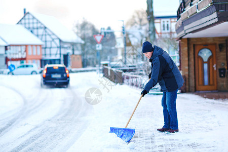 有雪铲的人在降雪期间在冬天清理人行道欧洲的冬天穿着温暖冬衣的年轻人德国的雪和天气混乱暴风雪和大图片