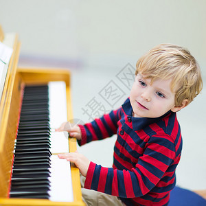 两岁快乐蹒跚学步的男孩弹钢琴幼儿的早期音乐教育孩子在学图片