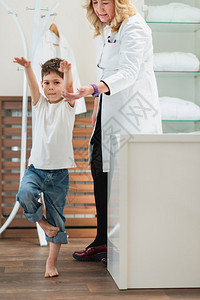 物理治疗师和小男孩做体检站在一条腿图片
