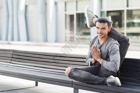 在市区长凳上练习高级瑜伽姿势的人图片
