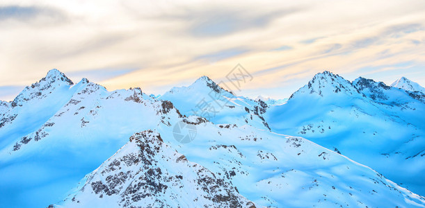 日落时在云层中的蓝色高山上的雪景全图片