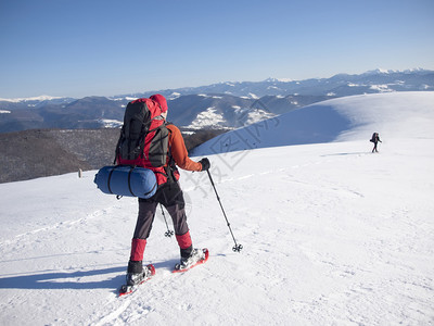 穿着雪鞋和登山杖的人进入山区图片