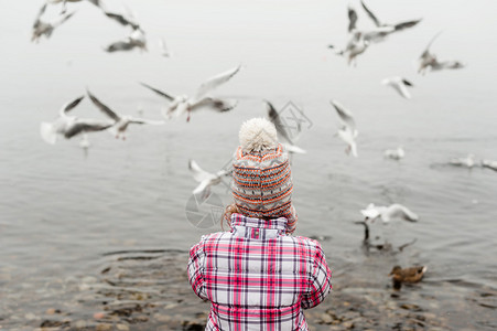 冬天在湖边喂鸟的小女孩穿着温暖图片