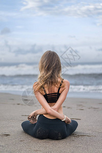 女青年在莲花中练瑜伽时的后视线用手臂从图片