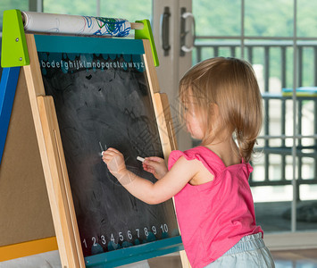 两岁的小女孩在黑板上画粉笔用双手绘图片
