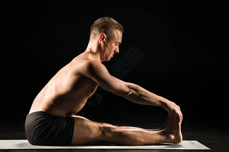 男人用直腿坐着做瑜伽用黑色的手孤背景图片