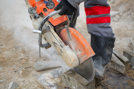 切割混凝土瓷砖沥青或混凝土切割机和工人靴建筑工人使用混凝土锯图片