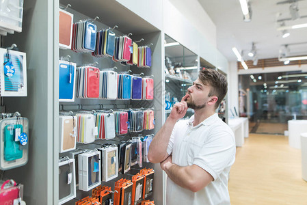 有思想的人在现代电子商店的配件部门为智能手机选择手机壳在科技商店购买图片