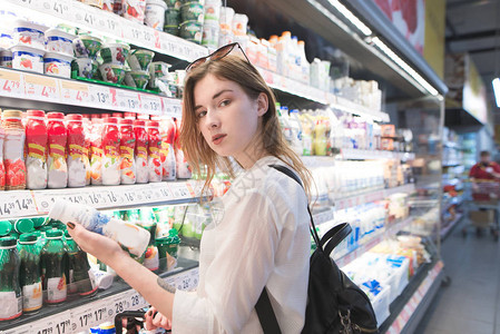 年轻时尚的女人站在她手中的酸奶超市图片