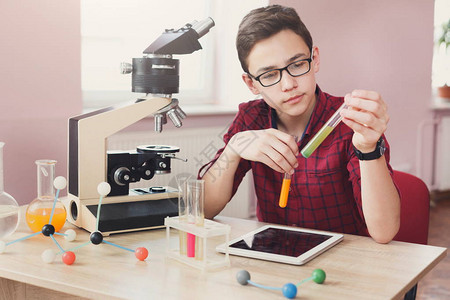集中的十几岁男孩在实验室用试剂进行化学研究图片