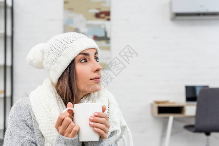 穿着温暖衣服的有体贴心的年轻女人在家端着图片