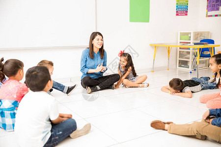 一群学龄前学生和他们的老师坐在教室地板上图片