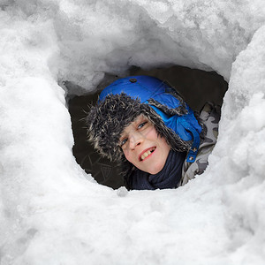 年轻男孩在雪山洞外看着他在雪上漂图片