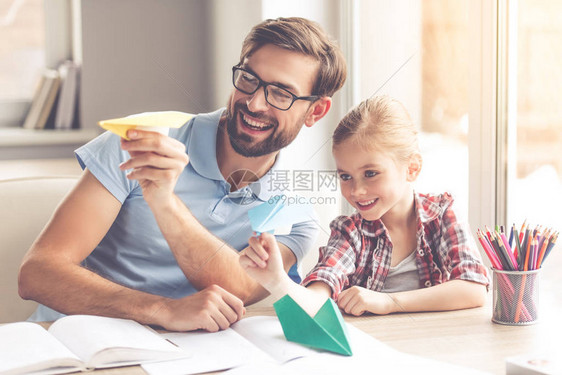 英俊的父亲和他可爱的小女儿一边玩纸飞机图片