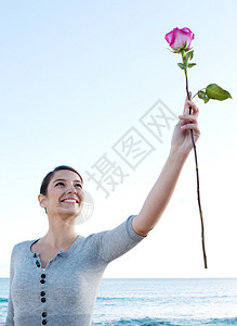 一位迷人的年轻女子将手臂举到蓝天的概念肖像视图中图片