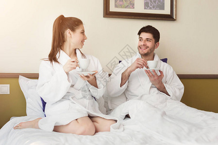 情侣坐在酒店房间的床上喝咖啡或茶图片
