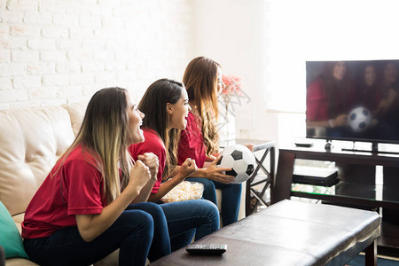 三组足球迷在电视上看球赛在球队进球后背景图片