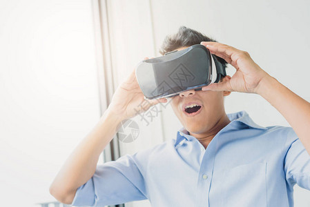 亚洲男子在客厅佩戴虚拟现实眼镜箱头耳机背景图片