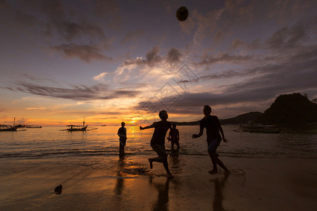 日落时在海滩上踢足球图片