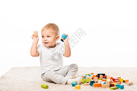 可爱的小可爱男孩在地毯上玩木砖块孤立在图片