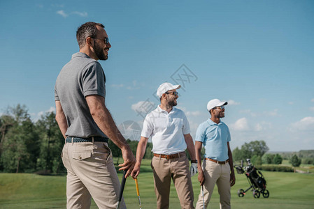青年多族裔高尔夫球运动员站立在球场上图片