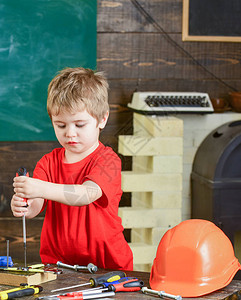 集中的孩子用双手将螺钉固定在木板上在维修车间工作的金发男孩学龄前儿图片