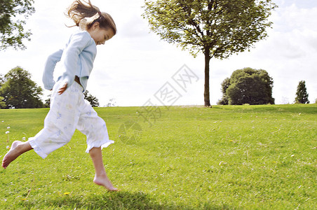 小孩子在公园的绿草上跳跃图片
