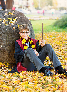 戴眼镜的男孩坐在秋天公园里图片