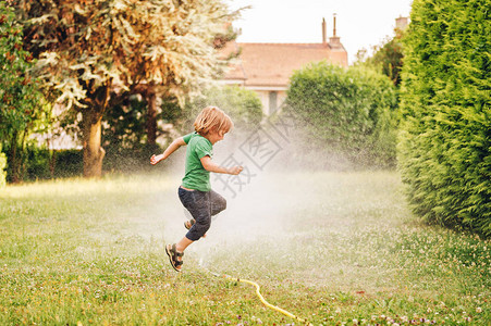 孩子玩花园洒水器跳过图片