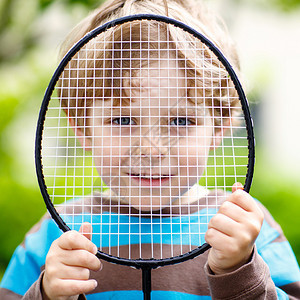 在家庭花园玩羽毛球的可爱滑稽小男孩图片