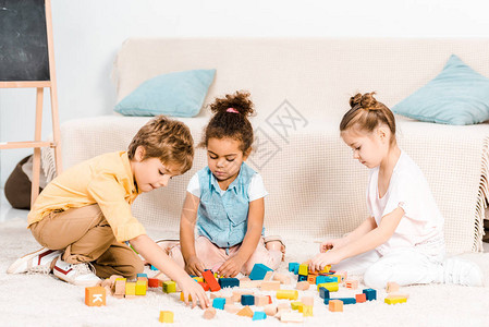 可爱的小孩在地毯上玩彩色方块图片